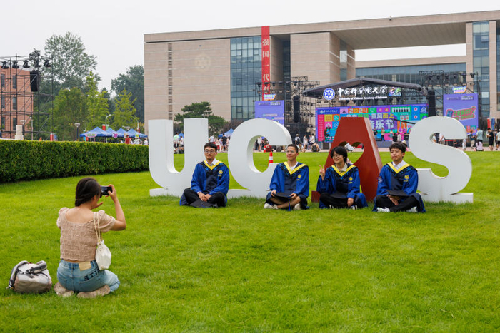 草坪上，中国科学院大学雁栖湖校区的毕业生们拍照留影。新京报记者 王子诚 摄