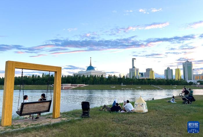 6月29日，人们在哈萨克斯坦首都阿斯塔纳伊希姆河畔休息。（图源：新华社）