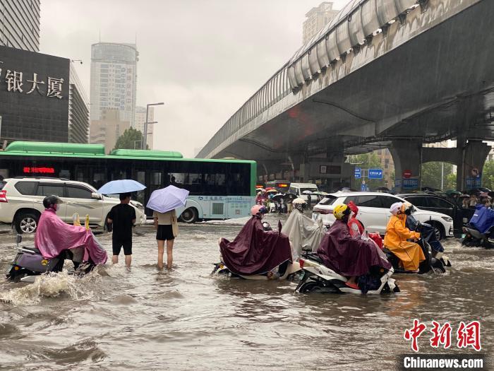 7月8日上午，郑州市花园路与农业路口，市民冒雨出行。范晓恒 摄