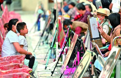 中央大街上的画像师为市民和游客画像，成为百年老街的独特风景。郭俊峰摄/光明图片