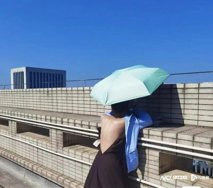 网友一边撑伞一边晒背