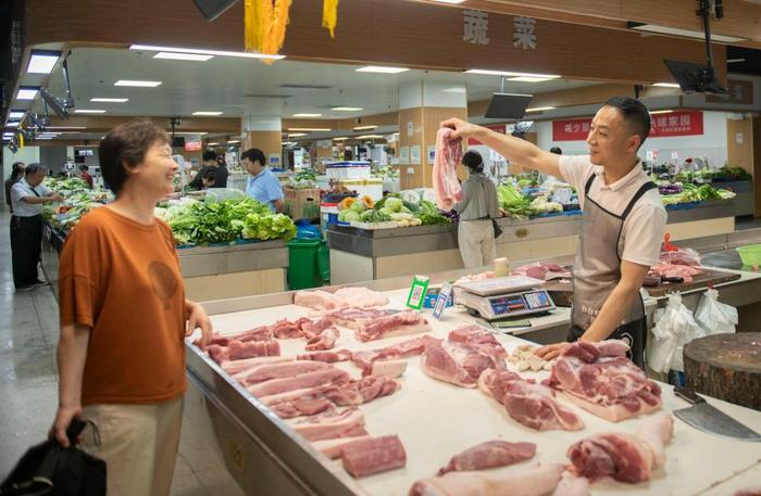 6月28日，在黄山市屯溪区阜上邻里中心菜市场，商户向顾客展示猪肉。新华社记者傅天 摄