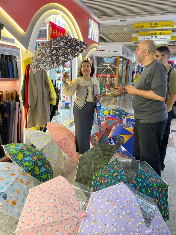 张吉英向两位埃及客人介绍店里的伞。图 / 每日人物摄