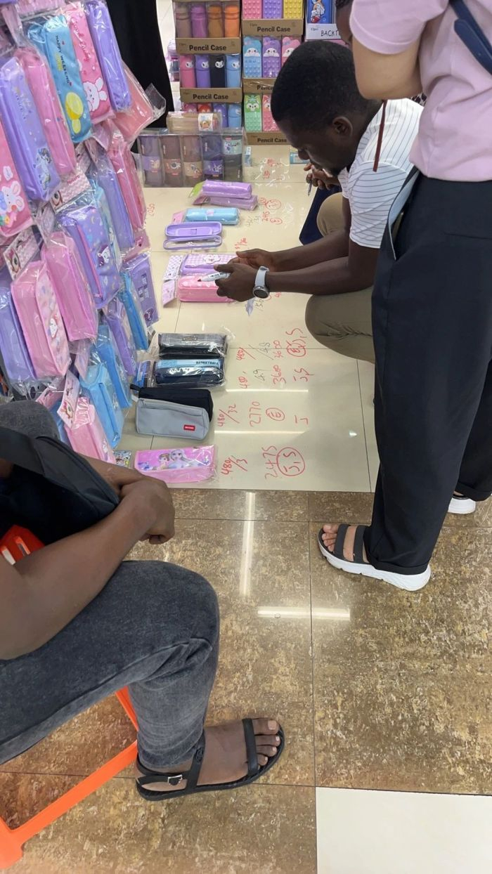 外商蹲在地上，用记号笔标记了数字，分别对应着价格、批发件数、货号。开始一轮讨价还价。图 / 每日人物摄