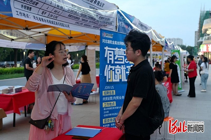 7月6日，在衡水市区爱琴海购物公园外的“人才夜市”上，大学毕业生张占德（右）与企业招聘人员交流。 河北日报记者 焦 磊摄