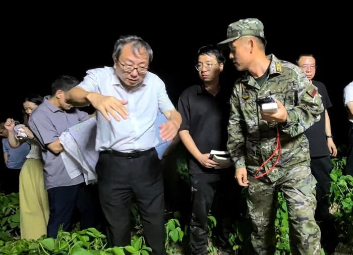   7月5日晚，湖南省洞庭湖水利事务中心专家陈文平（前排穿白衬衣者）在钱团间堤上与抢险人员讨论防守方案。新华社记者周楠 摄