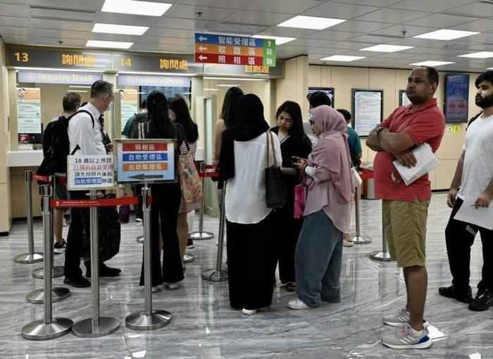 图为7月10日，有外籍人士到位于香港中旅证件服务港岛中心，申领“港澳居民来往内地通行证（非中国籍）”。（中新社）