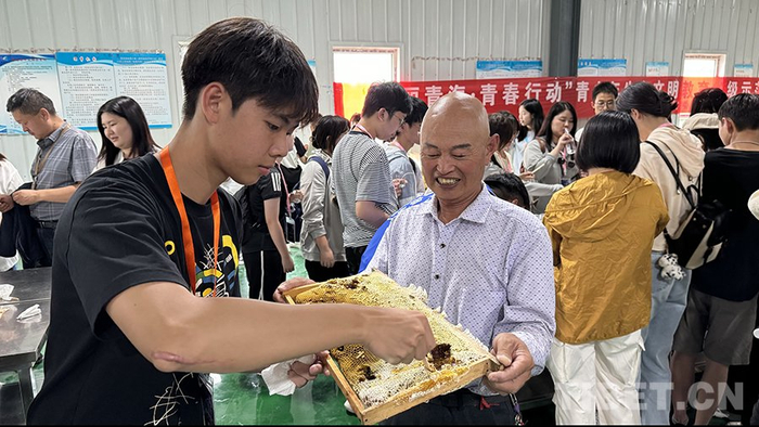 图为甄皓老人端着蜂巢板，邀请香港青少年品尝新鲜蜂蜜。摄影：易文文