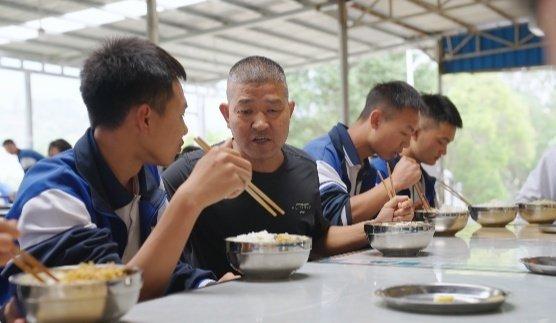 李家周老师在食堂与学生一起用餐。