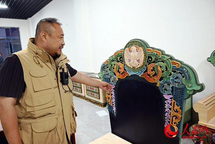 闻都苏向记者介绍蒙古族家具制作。人民网记者 刘艺琳摄