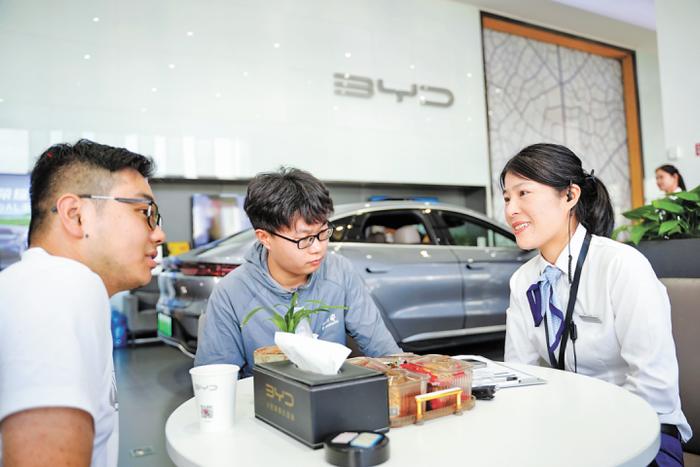 安徽合肥，比亚迪汽车销售员周婷（右）与客户洽谈。