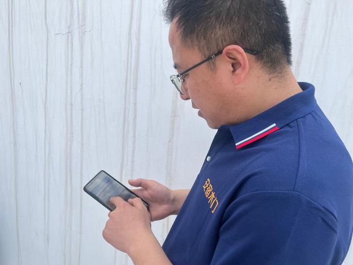 万林科的儿子万义飞在手机上查询用水量和缴费情况。新华社记者 任玮 摄