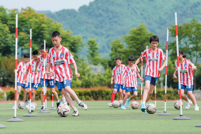 马安镇中心小学组织学生进行足球绕杆训练。