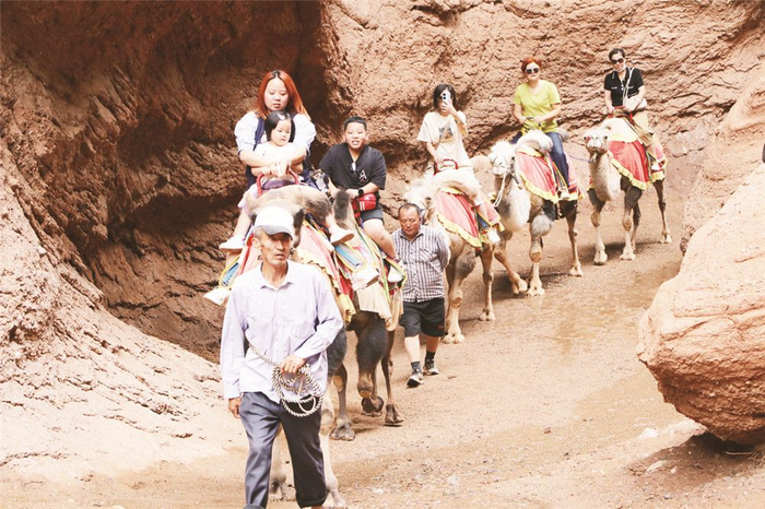 游客在新疆天山神秘大峡谷骑骆驼游玩。陈显锋 摄 