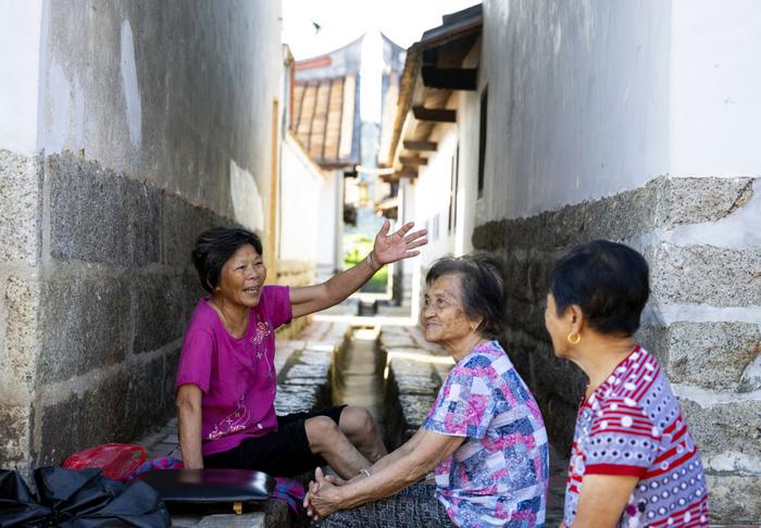 埭美村村民在古厝间乘凉聊天（7月10日摄）。