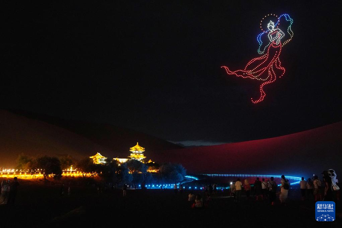   7月15日晚，游客在敦煌鸣沙山月牙泉景区观看无人机灯光秀。新华社记者 马宁 摄