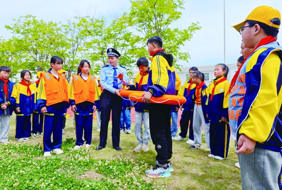 图为5月9日山东省枣庄市公安局峄城分局古邵派出所民警在辖区明德小学指导学生学习救生圈、救生衣的使用方法。              