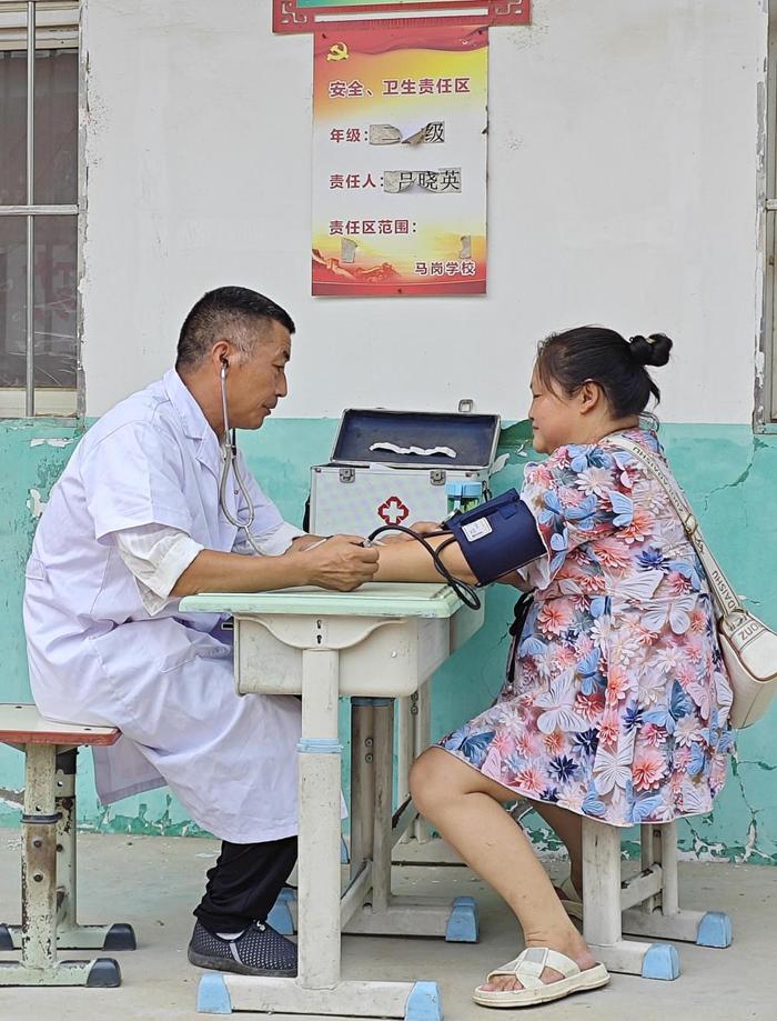   7月17日，在南阳市唐河县郭滩镇马岗村小学安置点，镇卫生所医生正在为居民量血压。新华社发（郑家宝摄）