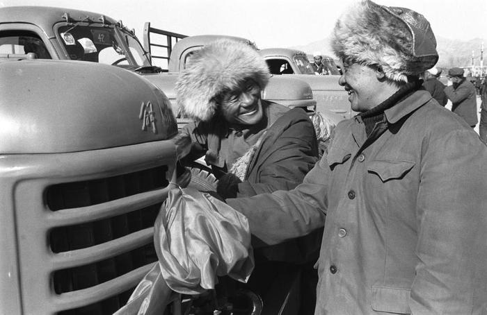 1985年，青海省果洛藏族自治州牧民扎杰（左）在新购买的解放牌卡车前和朋友交谈。