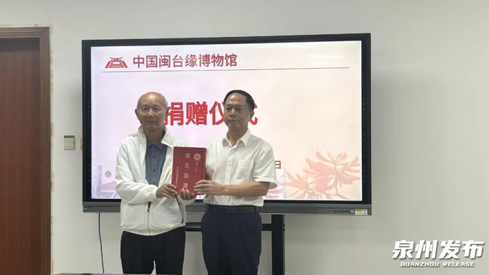 施明发先生（左）向中国闽台缘博物馆馆长郑国防捐赠《梁氏族谱》