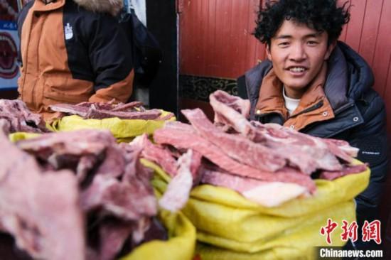资料图为2024年2月5日，藏历新年前，一位年轻的牧民在拉萨冲赛康市场附近卖自家晒制的风干牦牛肉。中新社记者 江飞波 摄