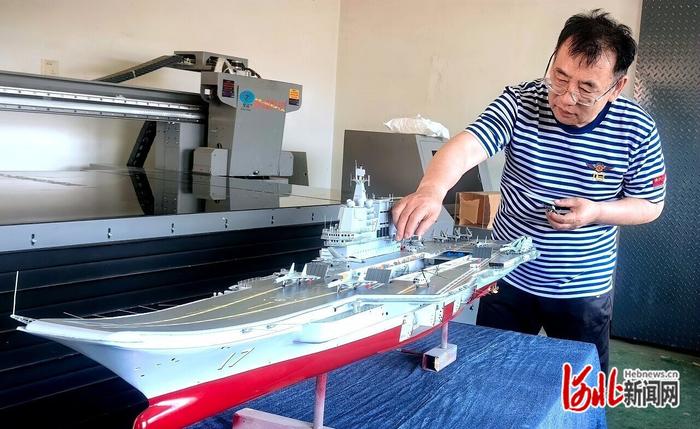 7月16日，万晓笠在车间里为“山东舰”航母模型安装舰载直升机模型。 河北日报记者 李建成摄