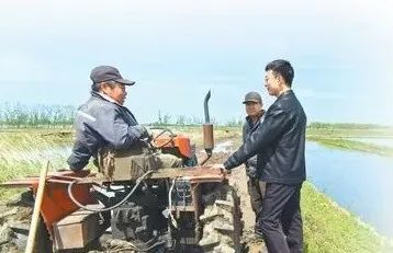 汪宏宇（右一）在田间了解农机使用情况。刘纯  摄