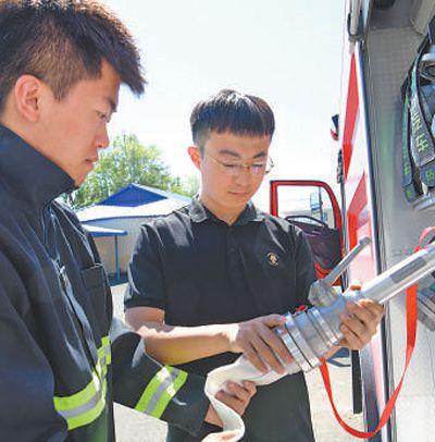 　　汪宏宇（右）在检查消防车。肖 鹏摄