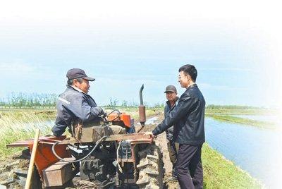 　　汪宏宇（右一）在田间了解农机使用情况。刘 纯摄