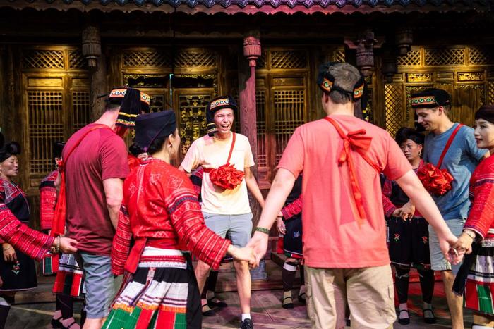 6月27日，在广西龙胜各族自治县龙脊镇黄洛瑶寨，外国游客与村民演员在红瑶民俗文化表演中互动。（杨植森 摄）