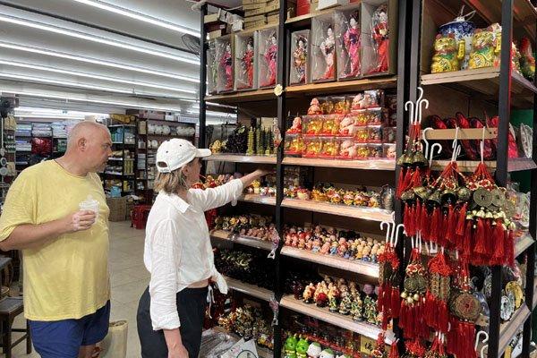 7月16日，外国游客在三亚街头的商店挑选中国文创产品。记者　程潇　摄