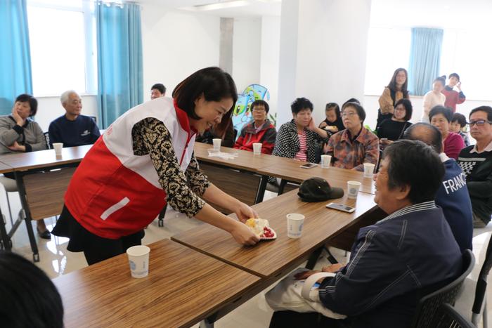 罗振奋在社区重阳节老年人集体生日会发放蛋糕。
