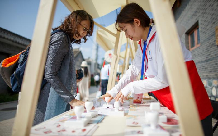 7月22日，游客在古北口镇一处文创摊儿前打卡盖章。新京报记者 王子诚 摄