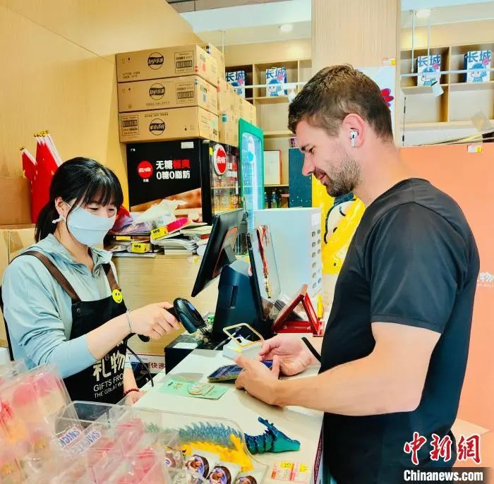 图为外籍游客在北京八达岭长城景区商店内体验电子支付。八达岭文旅集团供图
