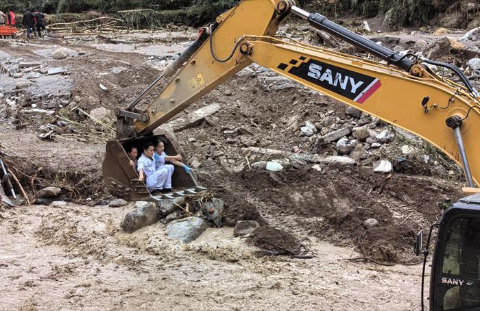 救援人员坐上挖掘机挖斗转运救治受灾村民。雅安市120急救中心供图