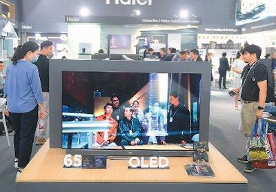 4月16日，在广东省广州市举行的第135届广交会上，客商在了解、选购海尔OLED电视。新华社记者 卢汉欣摄