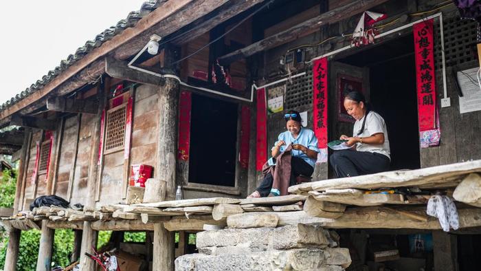 天门村村民陆大珍（左）、王兴珍在吊脚楼上制作绣片（7月16日摄）。