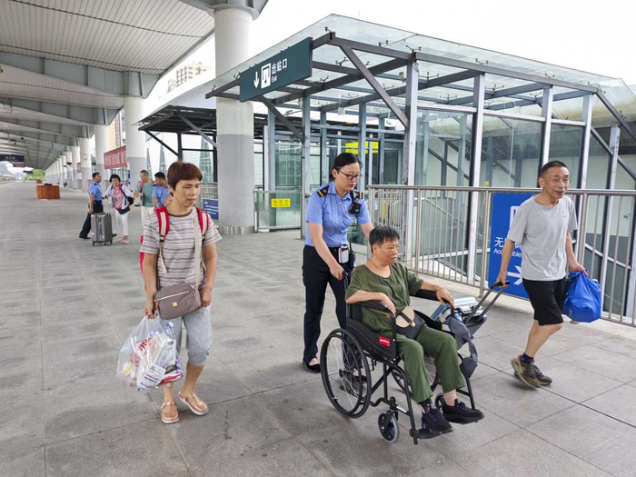 图为武铁利川站工作人员为重点旅客提供助行服务。（陈龙　摄）