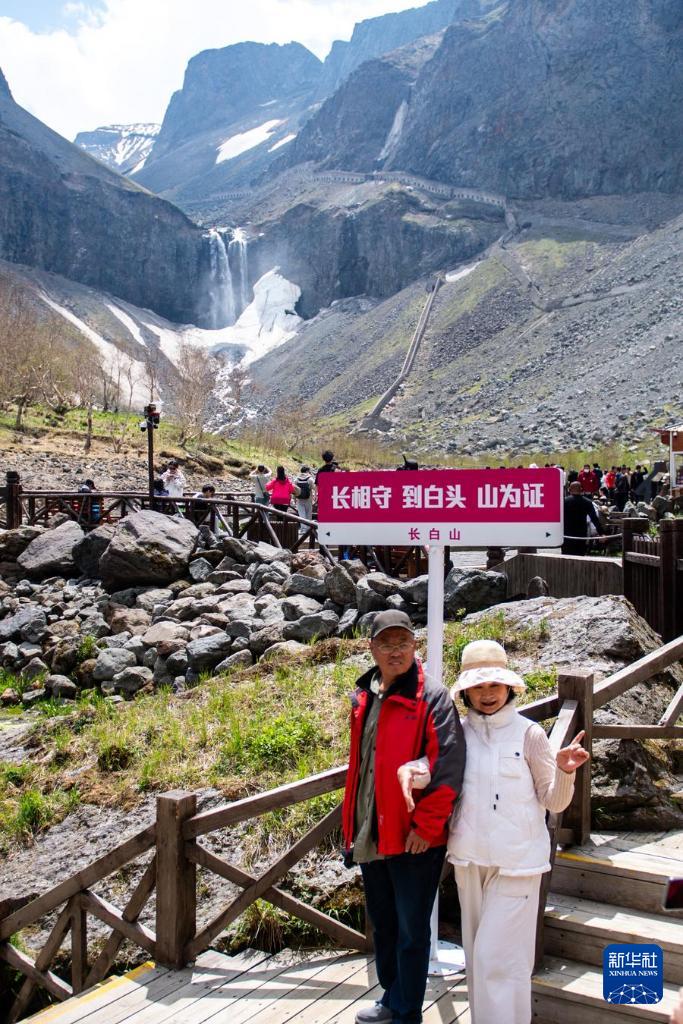 2024年6月5日，游客在长白山北景区瀑布前合影留念。新华社记者 许畅 摄