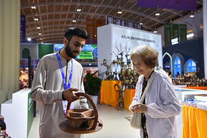 巴基斯坦展区的展商向一名顾客推介特色商品（2024年7月23日摄）。新华社记者 刘莲芬 摄