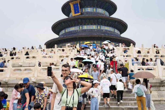   7月9日，两名外国游客在北京天坛公园祈年殿前自拍合影。新华社记者 鞠焕宗 摄