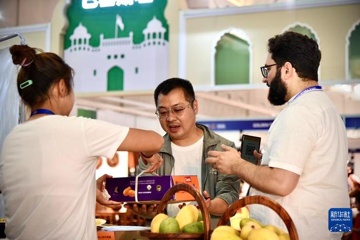 7月24日，巴基斯坦参展商阿德南·哈菲兹（右）向中国顾客介绍巴基斯坦芒果。新华社记者 王贤思 摄