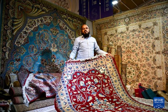7月24日，一名巴基斯坦参展商展示手工地毯。新华社记者 王贤思 摄