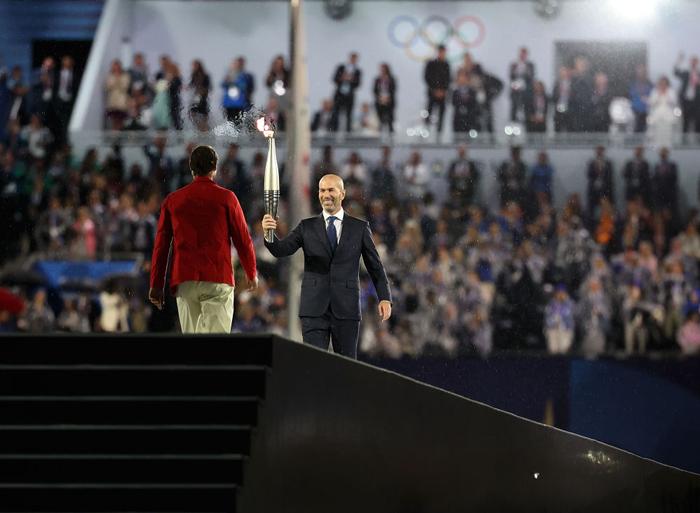↑火炬手西班牙网球运动员纳达尔（左）从上一棒火炬手法国足球名宿齐达内手中接过火炬。新华社记者 李明 摄