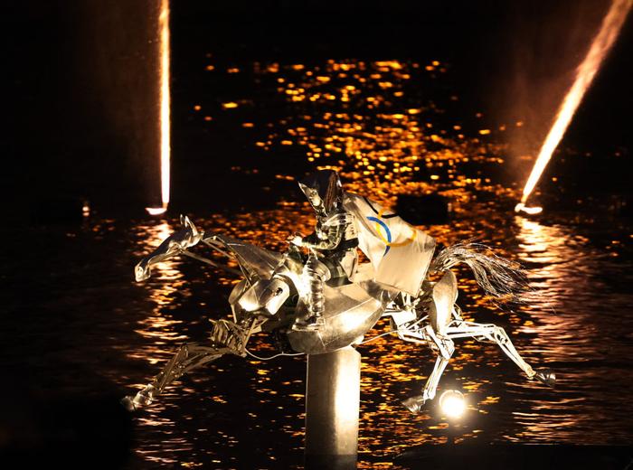 ↑女骑手弗洛里亚娜·伊塞尔身披奥林匹克五环旗沿着塞纳河“疾驰”。新华社记者 郭昱 摄