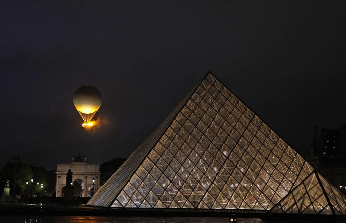 ↑热气球状的主火炬在卢浮宫的玻璃金字塔前点燃。新华社记者 孙非 摄