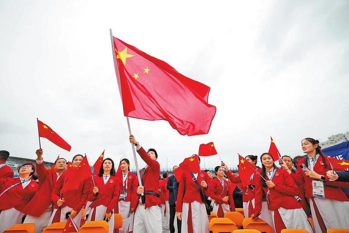 中国体育代表团旗手乒乓球选手马龙（中）在开幕式前挥舞国旗。 新华社记者 曹灿 摄