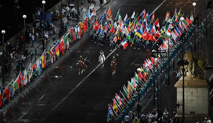 ↑女骑手弗洛里亚娜·伊塞尔（中）身披奥林匹克五环旗进入特罗卡德罗广场。新华社记者 程敏 摄