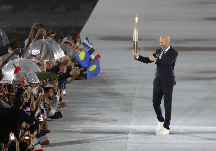 ↑法国足球名宿齐达内手持火炬向观众致意。新华社记者 高静 摄