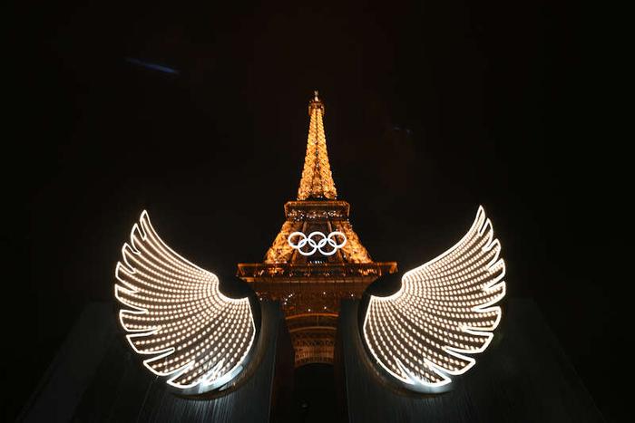 当地时间7月26日晚，巴黎奥运会开幕式，一对翅膀出现在埃菲尔铁塔旁，与铁塔组成了和平鸽的形象。视觉中国供图